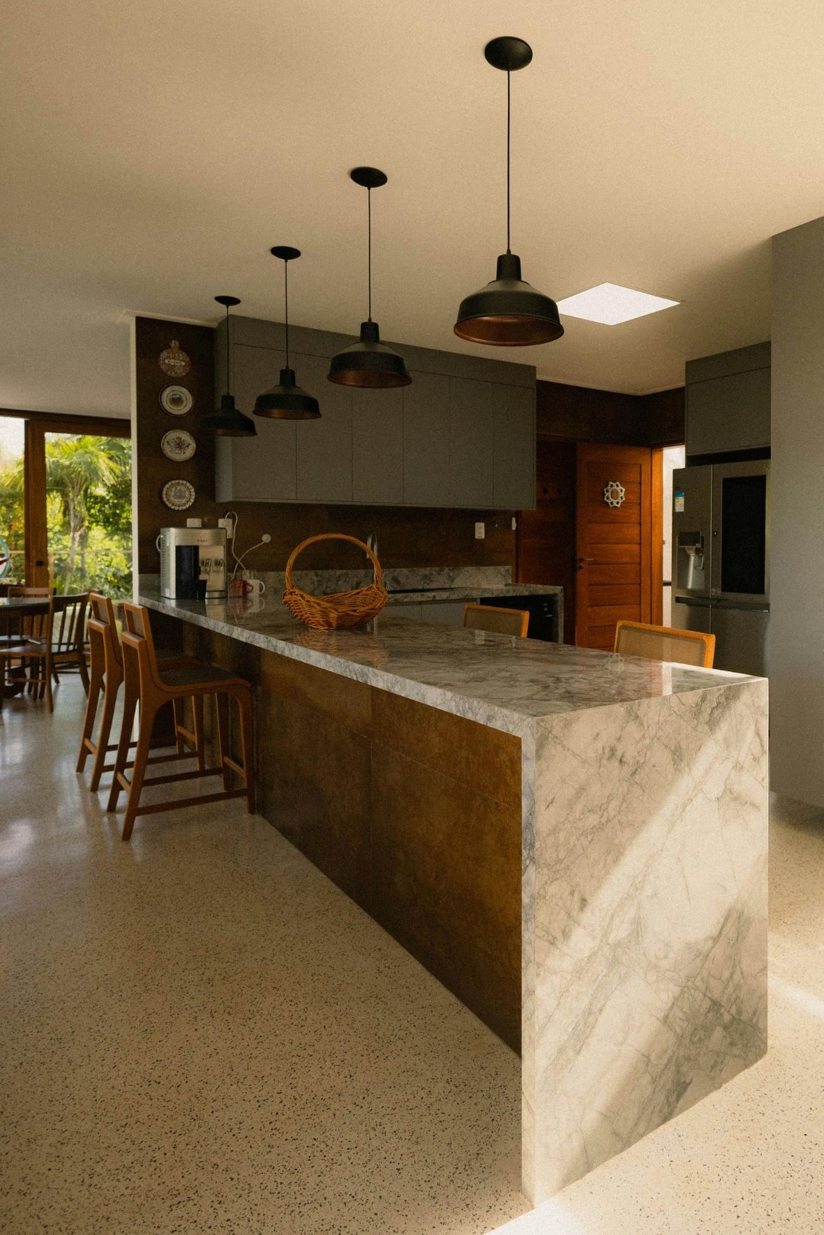 Cuisine contemporaine avec îlot central en bois clair, tabourets et hotte suspendue dans un intérieur résidentiel  à Limoilou